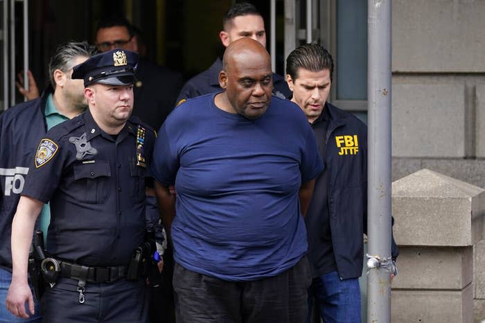 NYPD officials lead Frank James away from a police station.