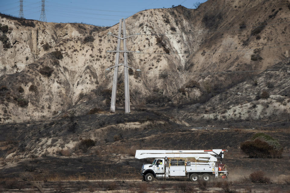 FILE - In this Oct. 15, 2019, file photo, SoCal Edison trucks arrive at the site of a transformer tower in Sylmar, Calif., suspected of being responsible for starting the Saddleridge fire. Southern California Edison will pay $2.2 billion to settle insurance claims from a deadly, destructive wildfire sparked by its equipment in 2018, the utility announced Monday, Jan. 25, 2021. (AP Photo/Christian Monterrosa, File)