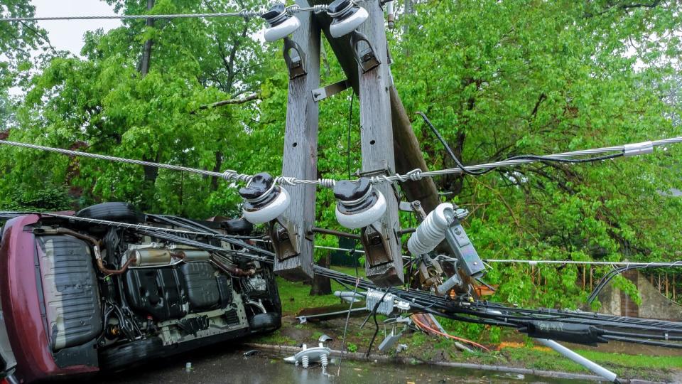 Overturned car on a road under downed power lines.