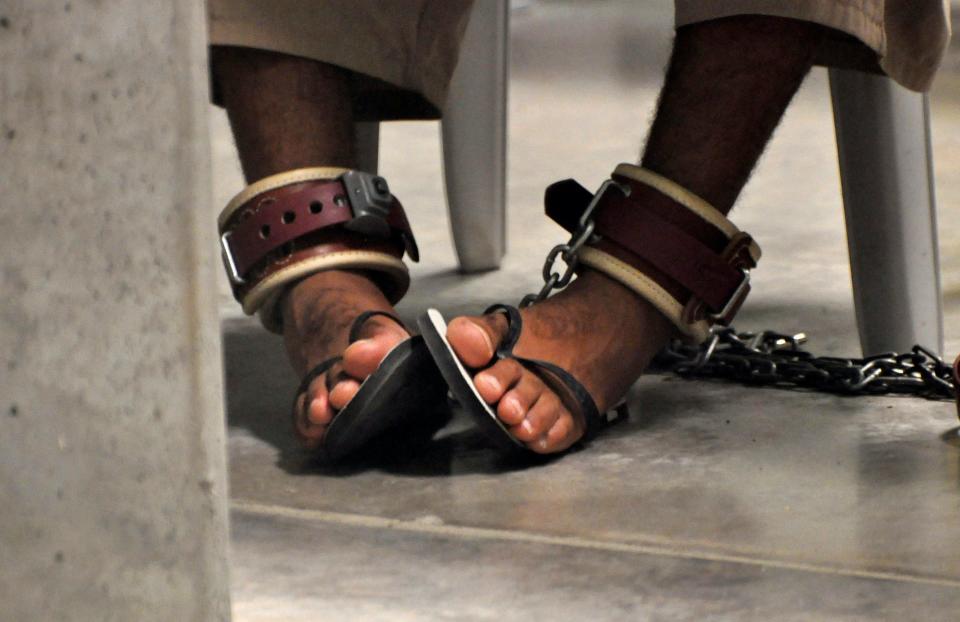 Feet in flip flops shackled to the floor