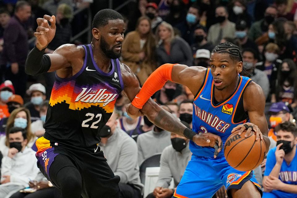 Oklahoma City Thunder guard Shai Gilgeous-Alexander drives past Phoenix Suns center Deandre Ayton (22) during the first half of an NBA basketball game, Thursday, Dec. 23, 2021, in Phoenix.