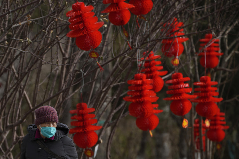 An elderly woman wearing a face mask walks by Lunar New Year decorations on display at a public park in Beijing, Thursday, Jan. 19, 2023. China on Thursday accused "some Western media" of bias, smears and political manipulation in their coverage of China's abrupt ending of its strict "zero-COVID" policy, as it issued a vigorous defense of actions taken to prepare for the change of strategy. (AP Photo/Andy Wong)