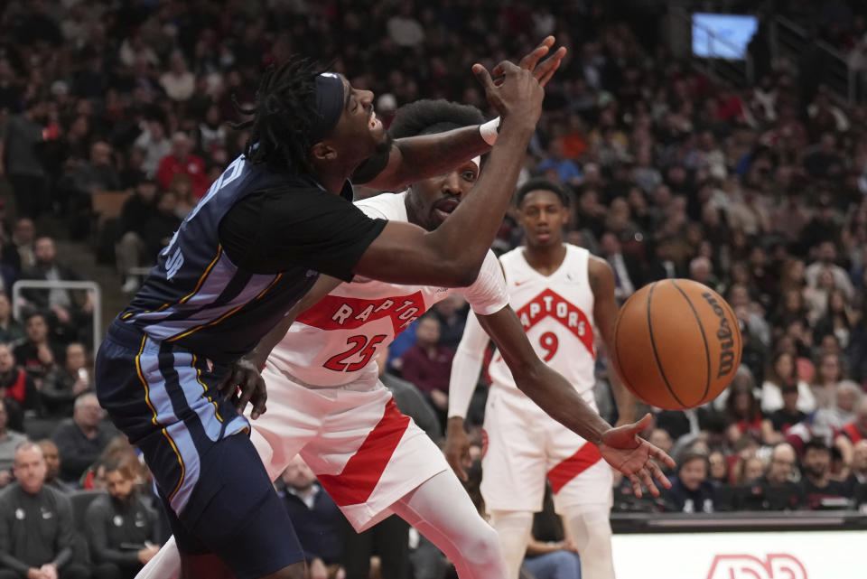 Memphis Grizzlies guard Vince Williams Jr., left, and Toronto Raptors forward Chris Boucher (25) battle for the ball during the first half of an NBA basketball game in Toronto Monday Jan. 22, 2024. (Nathan Denette/The Canadian Press via AP)