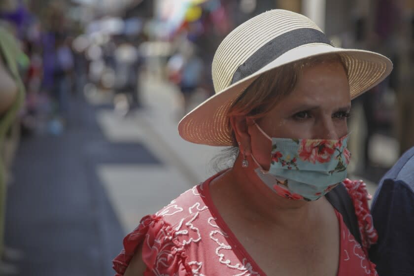 Los Angeles, CA - July 14: Sustained jumps in cases and hospitalizations fueled by the hyper-infectious BA.5 subvariant pushed Los Angeles County into the high COVID-19 community level Thursday, a shift that could trigger a new public indoor mask mandate by the end of this month unless conditions improve. A woman in mask shops at Santee Alley on Thursday, July 14, 2022 in Los Angeles, CA. (Irfan Khan / Los Angeles Times)