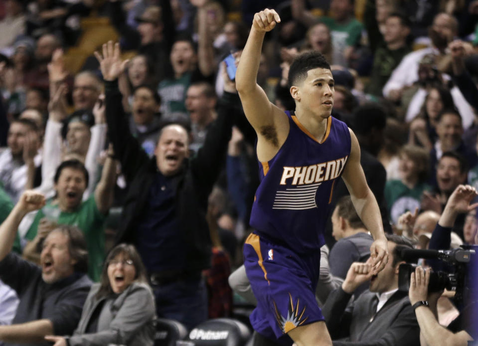 Phoenix Suns guard Devin Booker gestures after he scored a basket, as fans cheer him at TD Garden in the fourth quarter of the Suns' NBA basketball game against the Boston Celtics, Friday, March 24, 2017, in Boston. Booker scored 70 points, but the Celtics wonp 130-120. Booker is just the sixth player in NBA history to score 70 or more points in a game. (AP Photo/Elise Amendola)