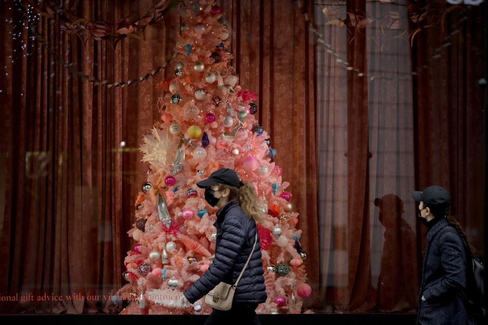 Women wearing face masks walk past a Christmas tree in the window of the Selfridges department store on Oxford Street, which is temporarily closed for in-store browsing with online collection possible from a collection point, during England's second coronavirus lockdown, in London, Monday, Nov. 23, 2020. British Prime Minister Boris Johnson has announced plans for strict regional measures to combat COVID-19 after England's second lockdown ends Dec. 2, sparking a rebellion by members of his own party who say the move may do more harm than good. (AP Photo/Matt Dunham)