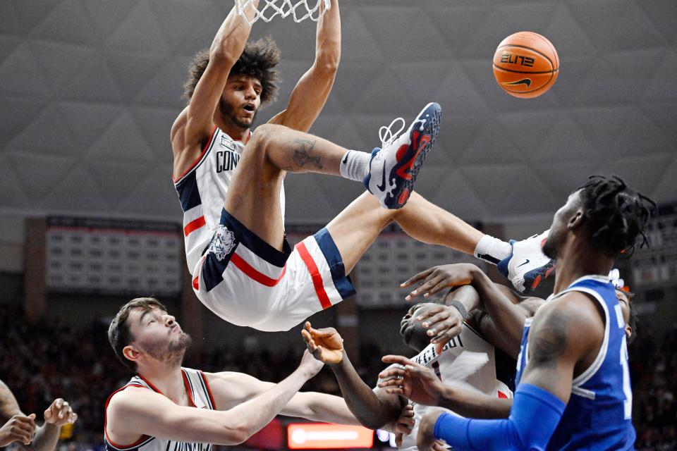 UConn's Andre Jackson Jr. dunks over teammates Alex Karaban, left, and Adama Sanogo in the second half of an NCAA college basketball game, Saturday, Feb. 18, 2023, in Storrs, Conn. (AP Photo/Jessica Hill)