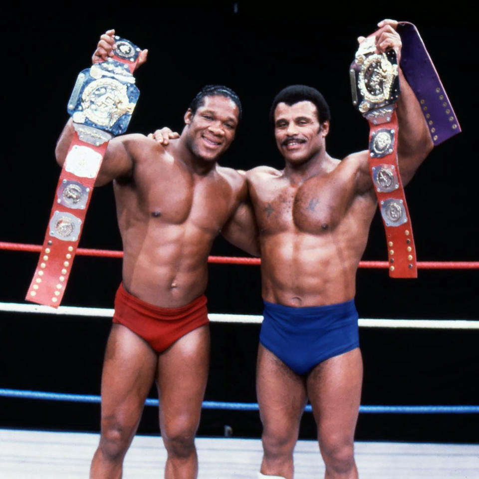 In this undated photo provided by WWE, Inc., Tony Atlas, left, and Rocky "Soul Man" Johnson pose in the ring with their championship wrestling belts. Johnson, a WWE Hall of Fame wrestler who became better known as the father of actor Dwayne “The Rock” Johnson, died Wednesday, Jan. 15, 2020. He was 75. (WWE, Inc. via AP)