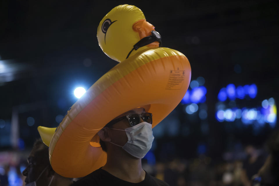 A protester wears an inflatable yellow duck, which has become a good-humored symbol of resistance during anti-government rallies, outside the headquarters of the Siam Commercial Bank, a publicly-held company in which the Thai King is the biggest shareholder, Wednesday, Nov. 25, 2020 in Bangkok Thailand. Pro-democracy demonstrators in Thailand on Wednesday again took to the streets of the capital, even as the government escalated its legal battle against them, reviving the use of a harsh law against defaming the monarchy. (AP Photo/Wason Wanichakorn)