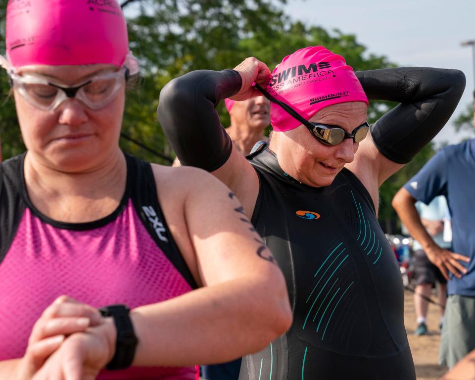 Carolyn Wood, 66, of Detroit, adjusts her goggles at left. Wood is representing Kotz Sangster law firm, one of the sponsors for Swim Across America Motor City Mile open water swim, a charity swim event for cancer research at Belle Isle on Friday, July 8, 2022.