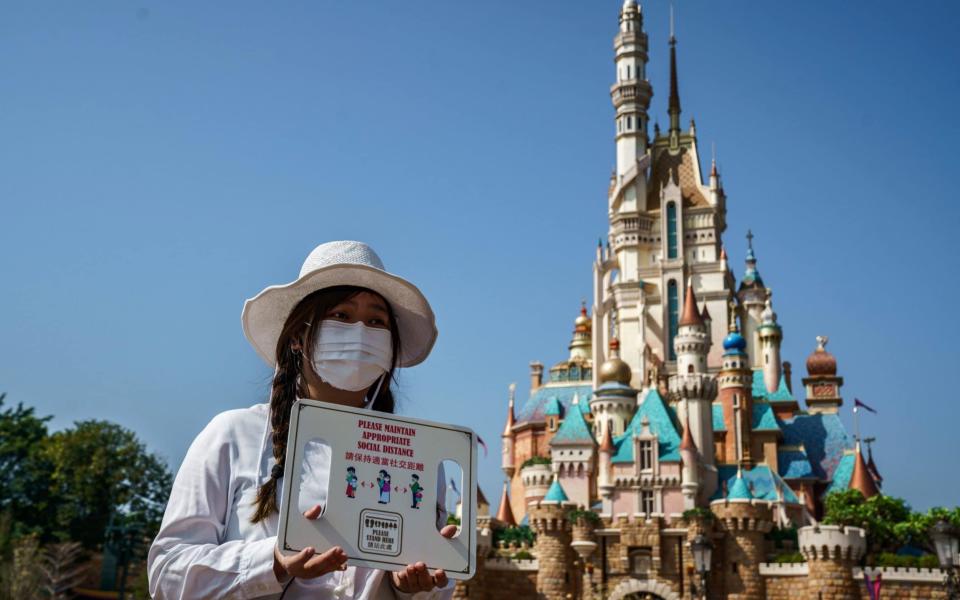 An employee holds a sign reminding visitors to maintain social distance  - Bloomberg