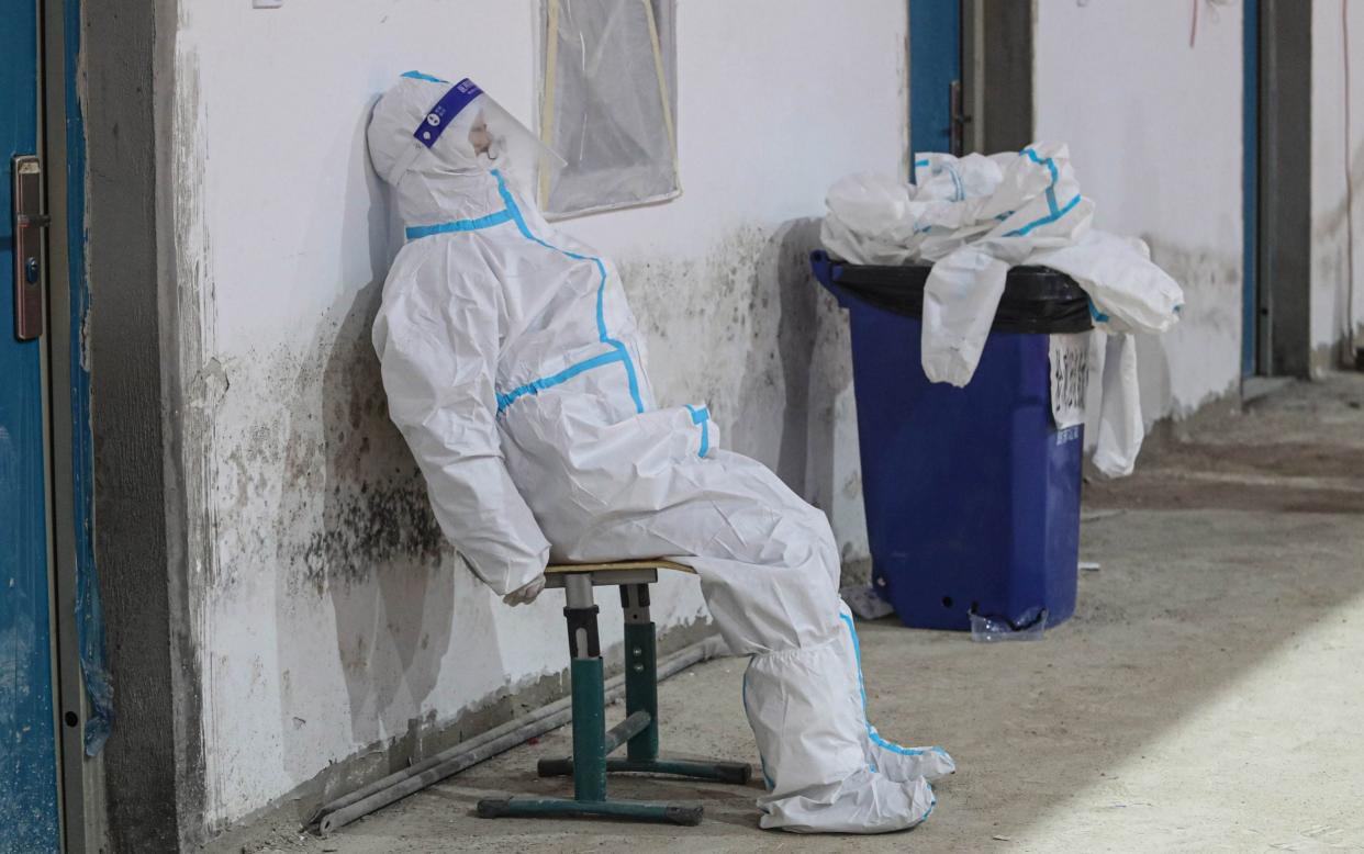 A medical worker wearing a protective suit has a rest at a temporary COVID-19 testing center on January 5, 2021 in Shenyang - VCG via Getty Images