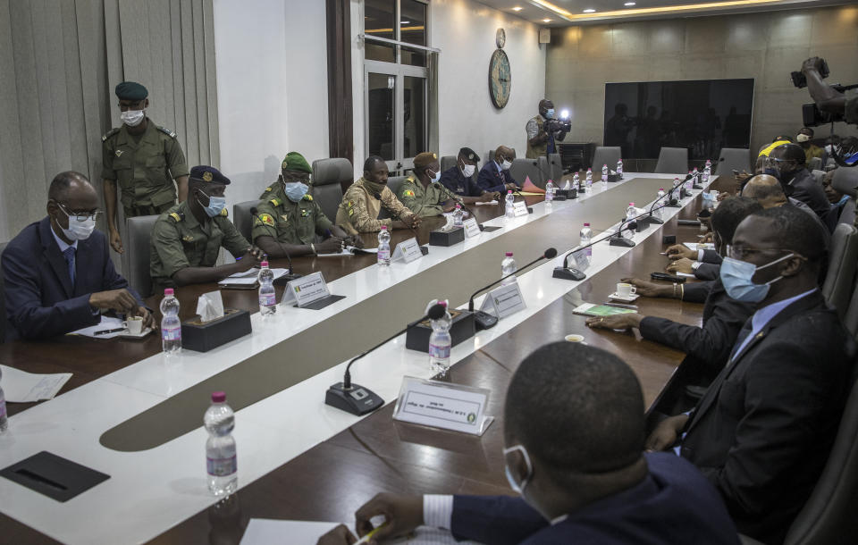 Representatives of the National Committee for the Salvation of the People, left of table, including Col. Assimi Goita, center of row, who has declared himself the group's leader, meet with a high-level delegation from the West African regional bloc known as ECOWAS, right of table, at the Ministry of Defense in Bamako, Mali, Saturday, Aug. 22, 2020. Top West African officials are arriving in Mali's capital following a coup in the nation this week to meet with the junta leaders and the deposed president in efforts to negotiate a return to civilian rule. (AP Photo)