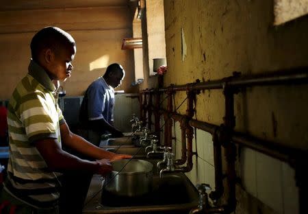Men wash pots in a communal kitchen at Jeppestown men's hostel in Johannesburg May 19, 2015. REUTERS/Siphiwe Sibeko