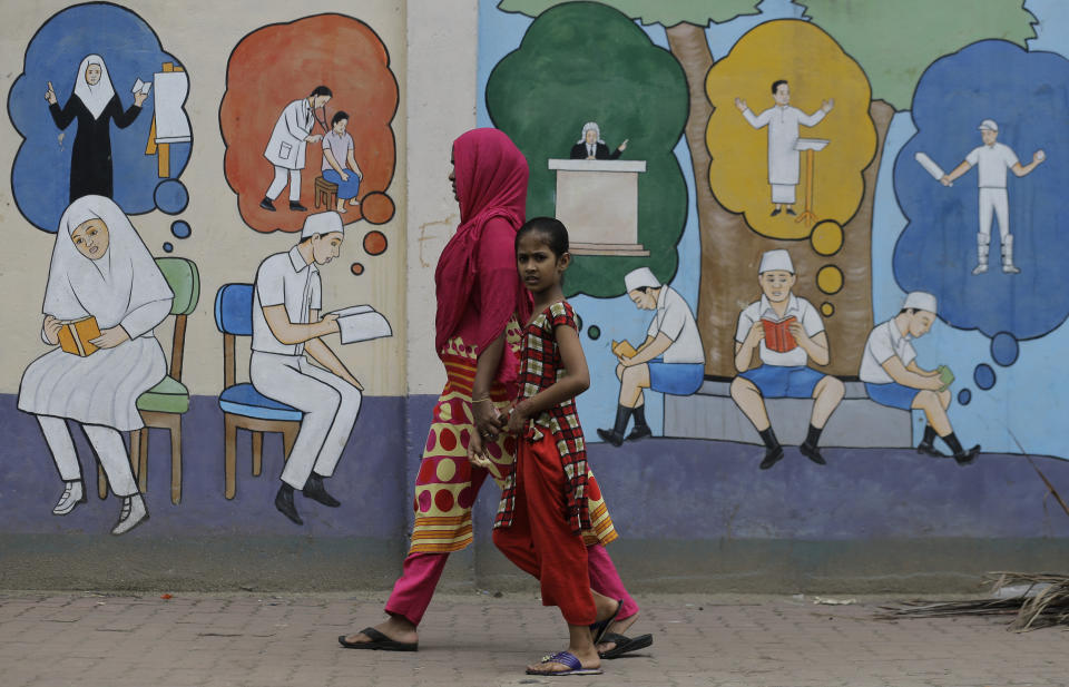 A Sri Lankan Muslim woman walks with a child past a wall decorated with graffiti in Colombo, Sri Lanka, Tuesday, Aug. 27, 2019. A Sri Lankan Muslim woman walks in a street in Colombo, Sri Lanka, Tuesday, Aug. 27, 2019. Islamic clerics in Sri Lanka asked Muslim women on Tuesday to continue to avoid wearing face veils until the government clarifies whether they are once again allowed now that emergency rule has ended four months after a string of suicide bomb attacks. (AP Photo/Eranga Jayawardena)