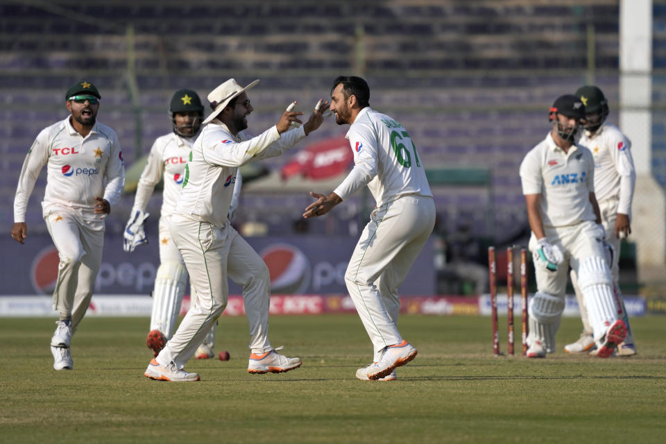 Pakistan's Agha Salman, center, celebrates with teammates after taking the wicket of New Zealand's Daryl Mitchell, right, during the first day of the second test cricket match between Pakistan and New Zealand, in Karachi, Pakistan, Monday, Jan. 2, 2023. (AP Photo/Fareed Khan)