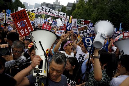 People hold placards and shout slogans as they protest against Japan's Prime Minister Shinzo Abe's security bill outside parliament in Tokyo August 30, 2015. REUTERS/Thomas Peter