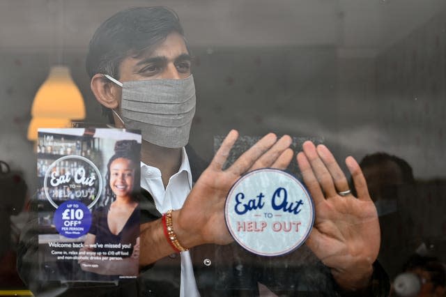 Chancellor Rishi Sunak places an Eat Out to Help Out sticker in the window of a business during a visit to Rothesay on the Isle of Bute, Scotland