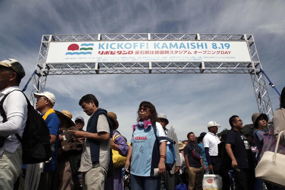 In this Sunday Aug. 19, 2018, photo, rugby funs queue up to enter Kamaishi Recovery Memorial Stadium to watch a memorial rugby match between the Kamaishi Seawaves and Yamaha Jubilo in Kamaishi, northern Japan. Japan opened the new stadium Sunday for the 2019 Rugby World Cup on the site of a school that was destroyed by a devastating tsunami in 2011. The stadium will host two matches in next year's World Cup, which will be played at 12 venues around Japan. (AP Photo/Koji Ueda)