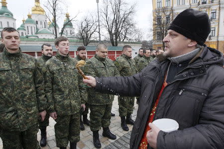 An Orthodox priest blesses members of the newly created Ukrainian interior ministry battalion "Saint Maria" during a ceremony before they head to a military training, in front of St. Sophia Cathedral, in Kiev, Ukraine, in this February 3, 2015 file photo. REUTERS/Valentyn Ogirenko/Files