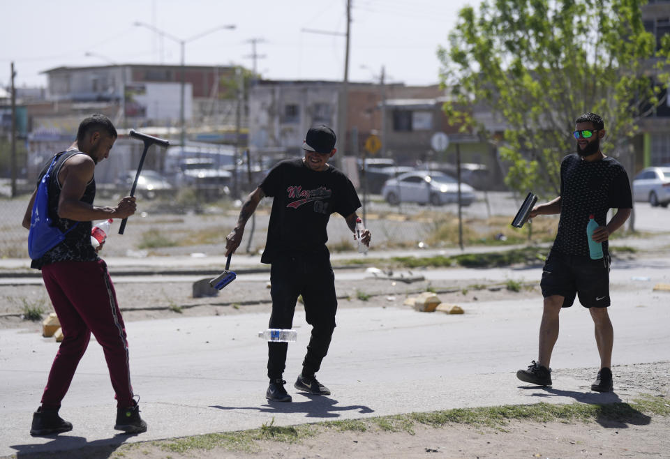 Irwing López, un trabajador de la construcción migrante venezolano de 35 años, a la derecha, bromea con otros migrantes en un semáforo mientras esperan a que los conductores laven los parabrisas para recibir propinas, en Ciudad Juárez, México, el jueves 30 de marzo de 2023. El amigo y compatriota de López, Samuel Marchena, fue detenido por agentes de inmigración y horas después se convirtió en uno de los 39 migrantes que murieron a principios de esta semana en un incendio en un centro de detención de migrantes. (Foto AP/Fernando Llano)