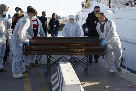 A coffin containing the body of a migrant who died, is carried off a navy ship at the Sicilian harbour of Empedocle December 5, 2014. REUTERS/Antonio Parrinello