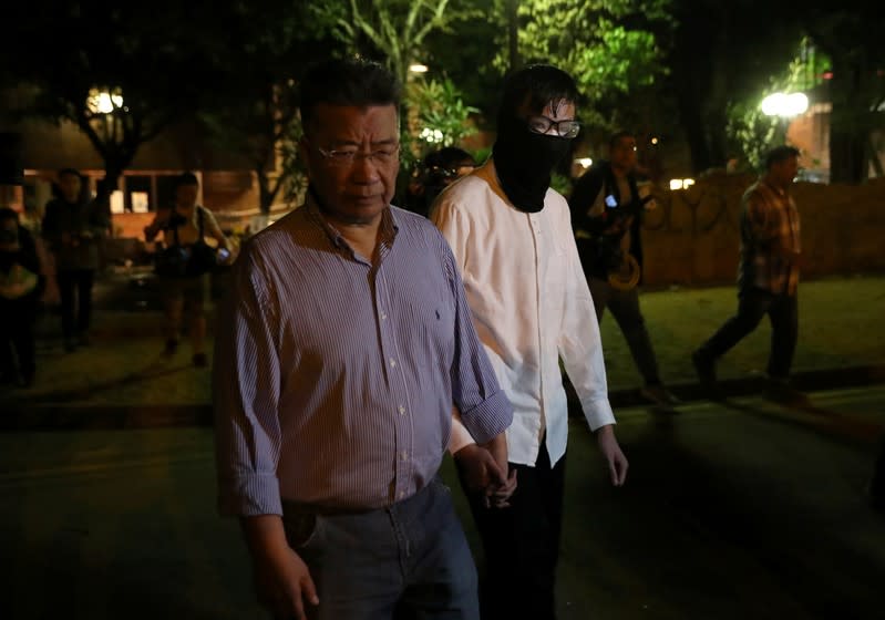 An anti-government protester is led out by Hong Kong businessman Lew Mon-hung, to give himself up to the police at Polytechnic University (PolyU) in Hong Kong