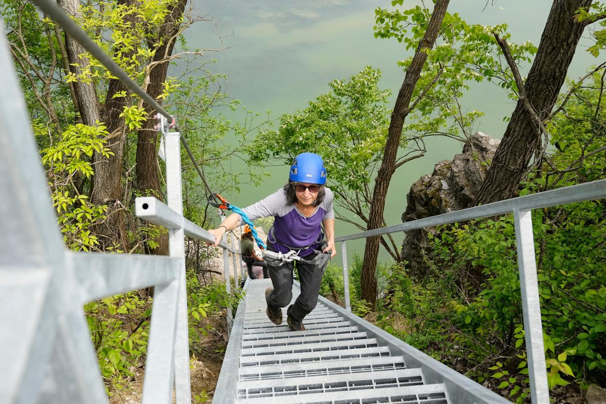 Loretta Graham, 66, ascends the metal staircase at the end of the via ferrata rock wall at Quarry Trails Metro Park in Columbus on May 11. The 1,040-foot guided climb, believed to be the first urban via ferrata in the country, reaches heights of over 100 feet.