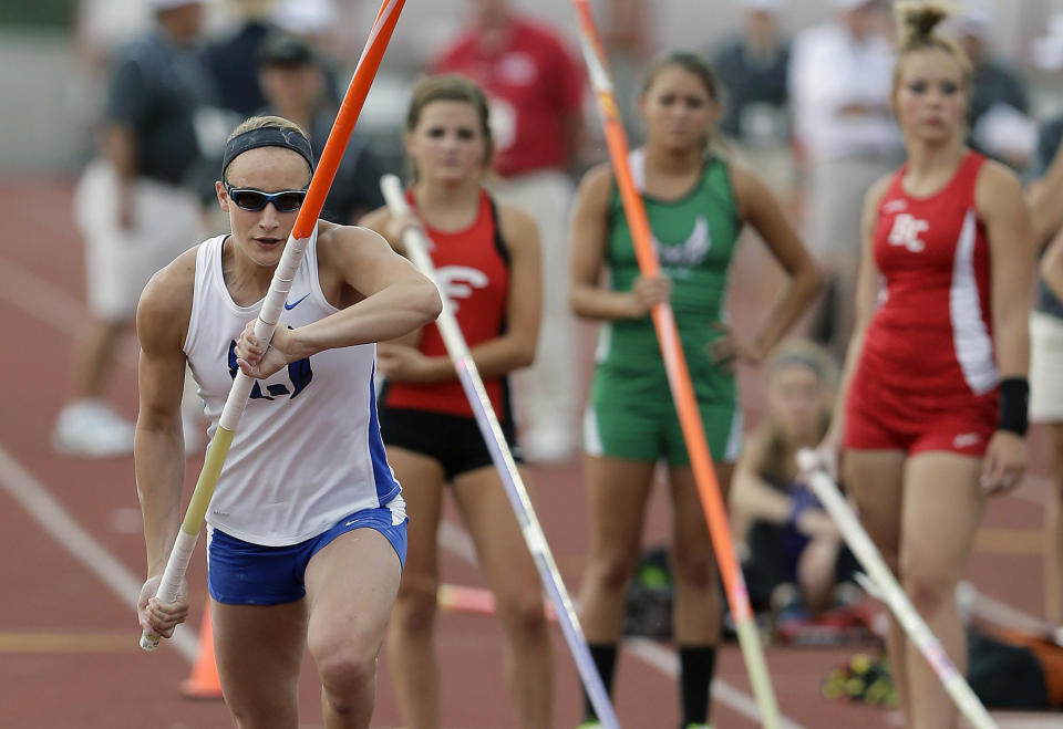 Emory Rains High School's Charlotte Brown, left, competes in the Girls 3A pole vault at the UIL State Track & Field meet, Friday, May 9, 2014, in Austin, Texas. Brown, a pole vaulter who happens to be legally blind, starts on the clap from her coach and counts her steps on her approach. (AP Photo/Eric Gay)