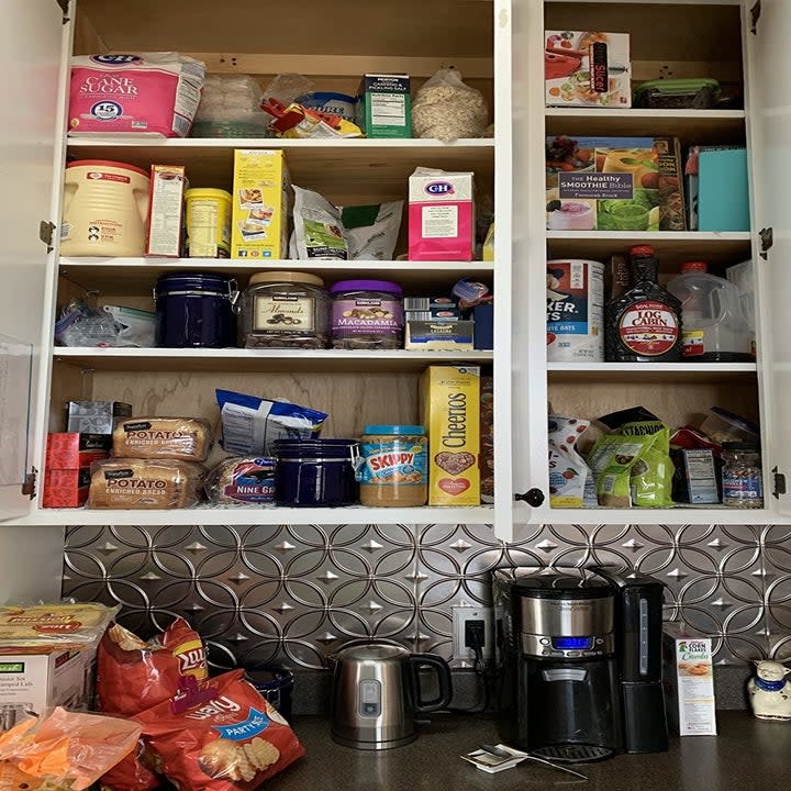 reviewer showing their cupboards completely overflowing with boxes and bags of dry goods