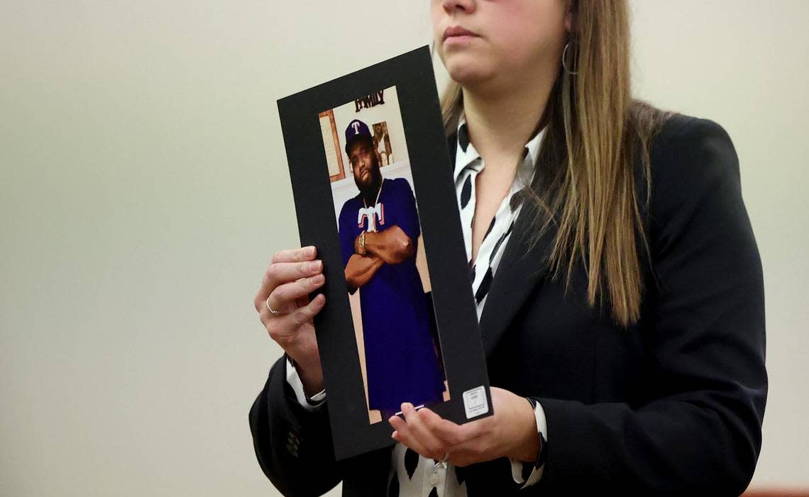 Assistant Criminal District Attorney Katie Owens holds a photograph of victim Kevin Brown during closing arguments in the murder trial of his son Braylin Brown on Nov. 9.