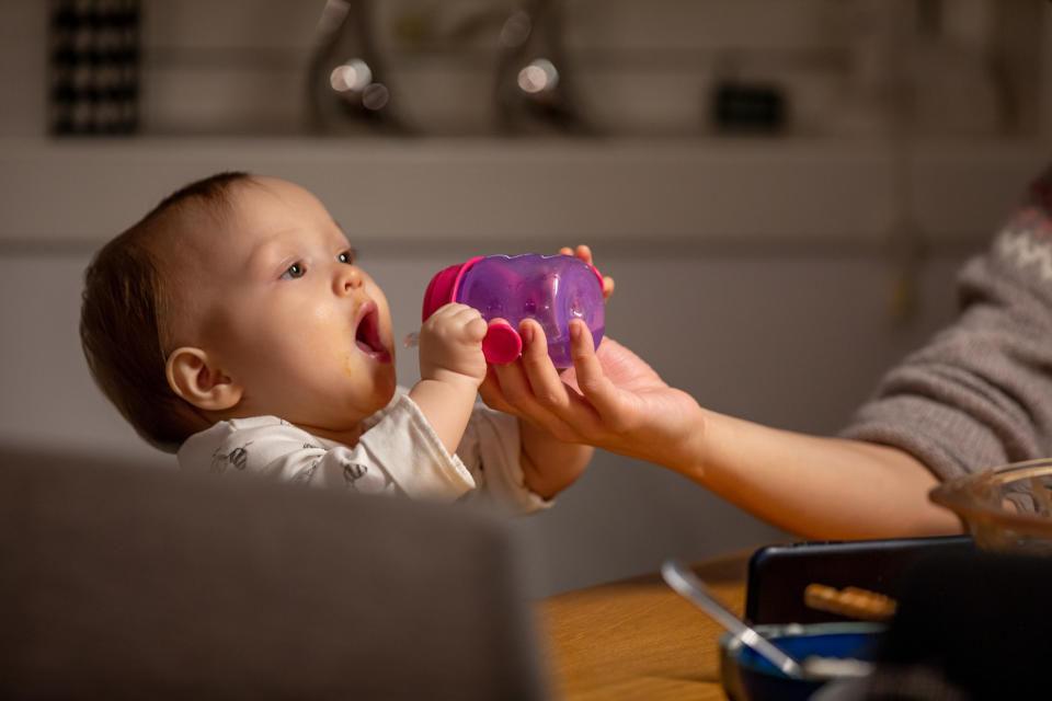 A parent handing a baby their bottle