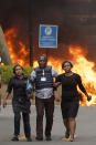 Security forces help civilians flee the scene as cars burn behind, at a hotel complex in Nairobi, Kenya Tuesday, Jan. 15, 2019. Terrorists attacked an upscale hotel complex in Kenya's capital Tuesday, sending people fleeing in panic as explosions and heavy gunfire reverberated through the neighborhood. (AP Photo/Ben Curtis)