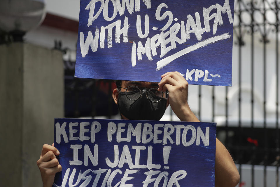 A protester holds a slogan during a rally outside the Department of Justice in Manila, Philippines on Thursday Sept. 3, 2020. A Philippine court has ordered the early release for good conduct of U.S. Marine Lance Cpl. Joseph Scott Pemberton convicted in the 2014 killing of transgender Filipino Jennifer Laude which sparked anger in the former American colony. (AP Photo/Aaron Favila)