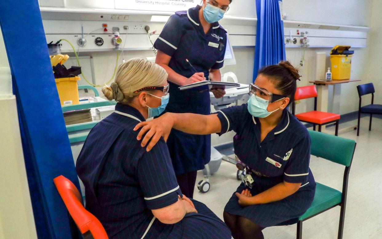 Matron May Parsons (right) is assessed by Victoria Parker (centre) during training in the Covid-19 Vaccination Clinic at the University Hospital in Coventry - PA