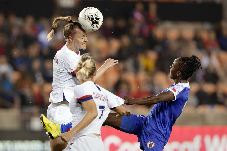 United States defender Becky Sauerbrunn, left, heads the ball as defender Abby Dahlkemper (7) is pulled by Haiti forward Sherly Jeudy, right, as she goes for the ball during the first half of a women's Olympic qualifying soccer match Tuesday, Jan. 28, 2020, in Houston. (AP Photo/Michael Wyke)