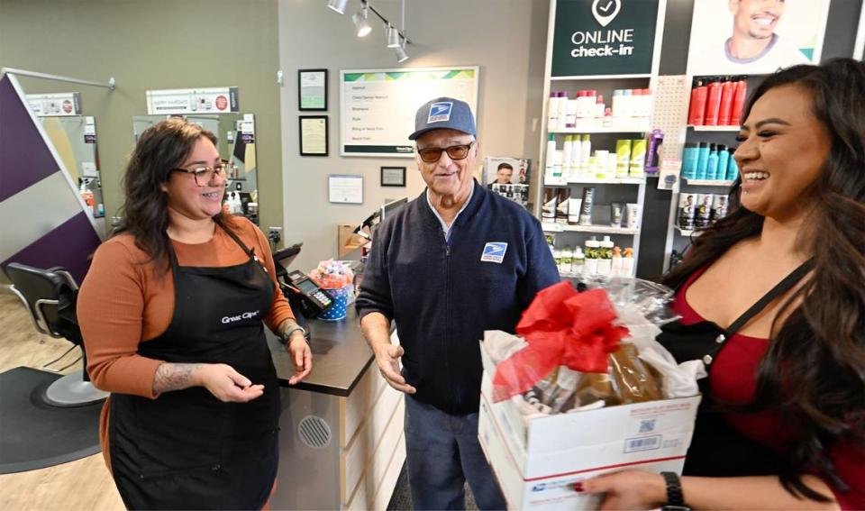 Las peluqueras de Great Clips Jasmine Delgadillo (a la izquierda) y Karen Sam, dan un regalo a Dave Costa mientras reparte el correo en McHenry Village en Modesto, California, el miércoles 27 de diciembre de 2023. Costa se jubila el miércoles después de más de 56 años en el Servicio Postal.