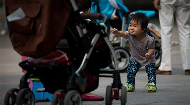 A toddler reacts to another as they play near their baby strollers at Ritan Park in Beijing Monday, Sept. 9, 2013. Photo: AP.