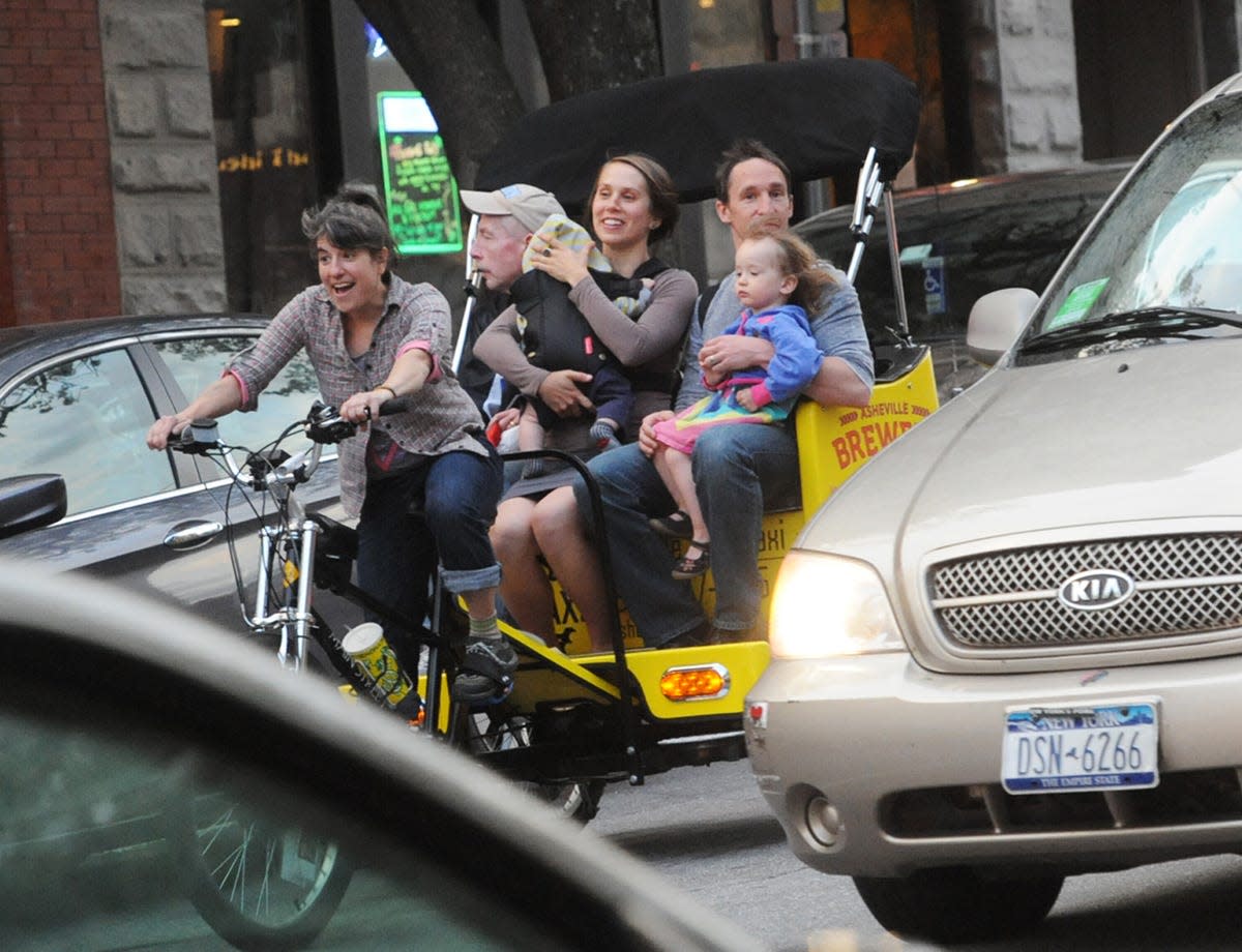 Jessie Lehamann drives a family around downtown in April on her pedicab. The 5-foot-tall rickshaw lady is a curious sight chugging up the hills of downtown Asheville, pedal-powering three or four people to drum circles, restaurants, bars, hotels and Pack Square, among other busker hangouts. http://blogs2.citizen-times.com/photography/2014/04/14/the-sunday-frame-taxi-driver-on-two-wheels/