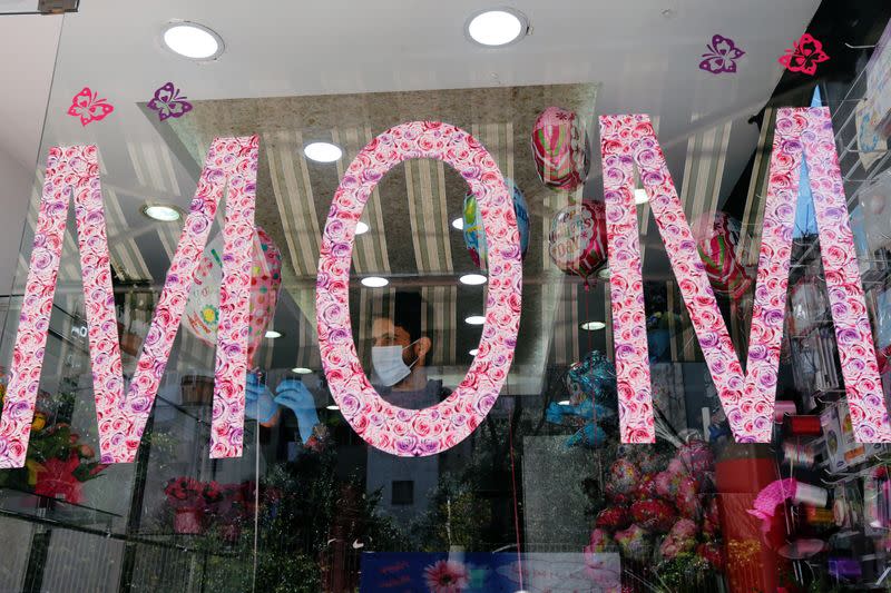 A worker is seen through a flower shop window as flower shops are open exceptionally for Mother's Day, in Beirut