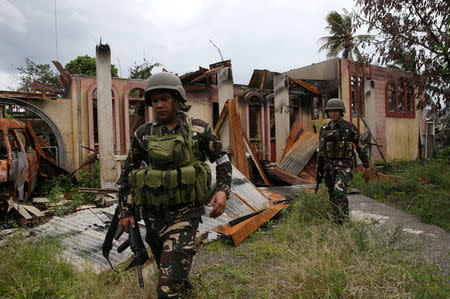 Soldiers walk past a damaged house after government troops cleared the area. REUTERS/Romeo Ranoco