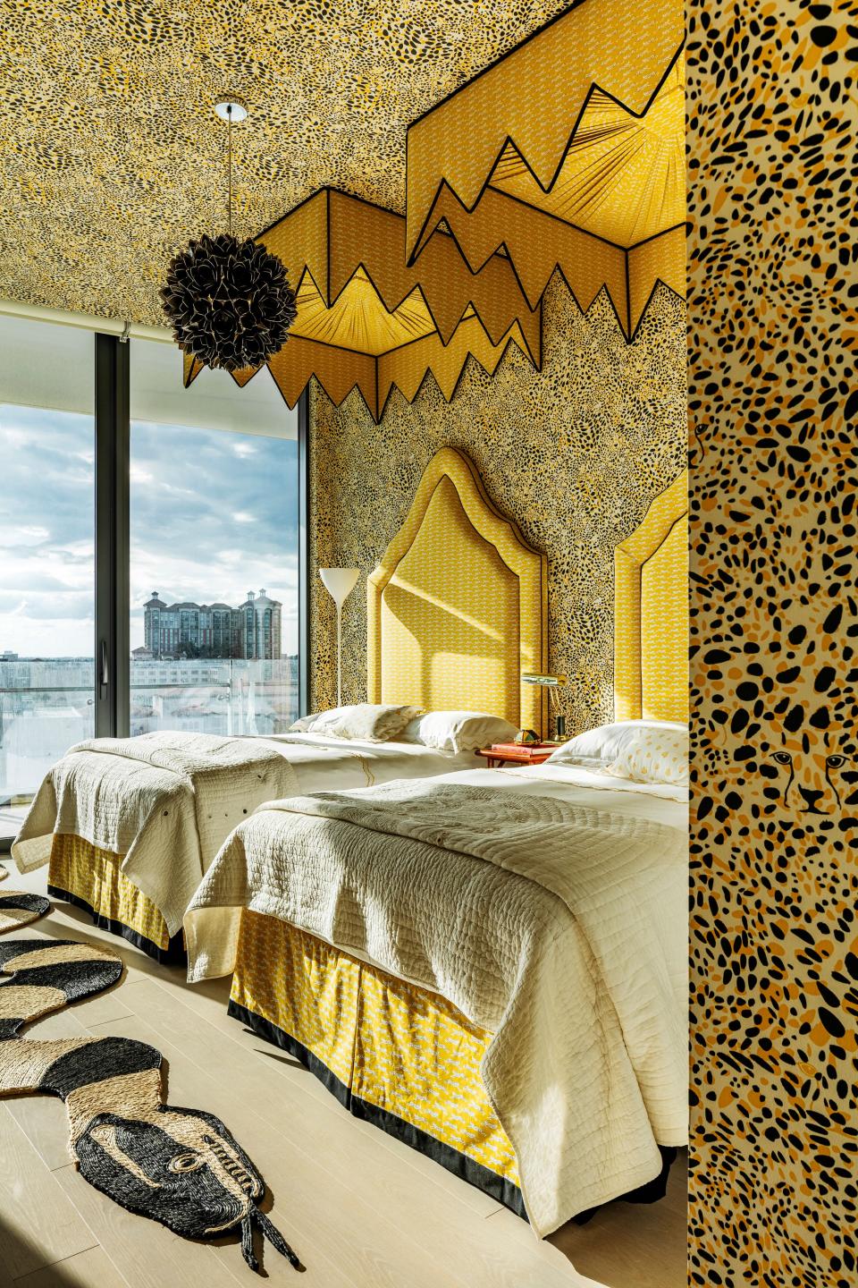 Canopies and a leopard-print wall covering bring whimsy to a guest bedroom.