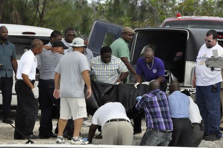 Rescue workers carry from a boat to a hearse the body of one of the victims of a small plane that crashed near the airport of Grand Bahama Island, in East Grand Bahama August 18, 2014. REUTERS/Vandyke Hepburn