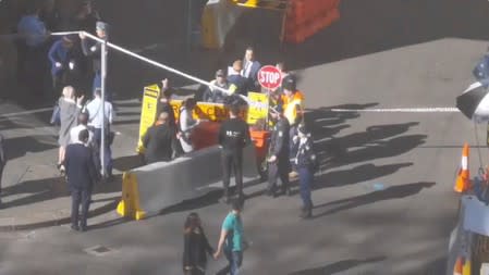 People walk past security officers standing around a barricaded area, following reports of a stabbing in the central business district of Sydney