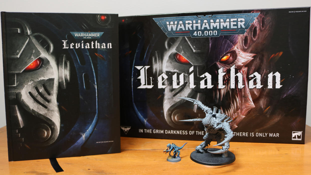  The Warhammer 40,000: Leviathan boxed set with the rule book and two miniatures set out on a wooden table 