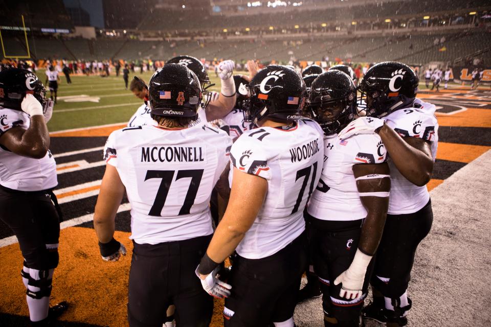 Cincinnati Bearcats offensive lineman Vincent McConnell (77) and Cincinnati Bearcats offensive lineman Colin Woodside (71) gathers up with other offensive linemen before the NCAA football game between Miami (Oh) Redhawks and Cincinnati Bearcats on Saturday, Sept. 8, 2018, in Downtown Cincinnati. 