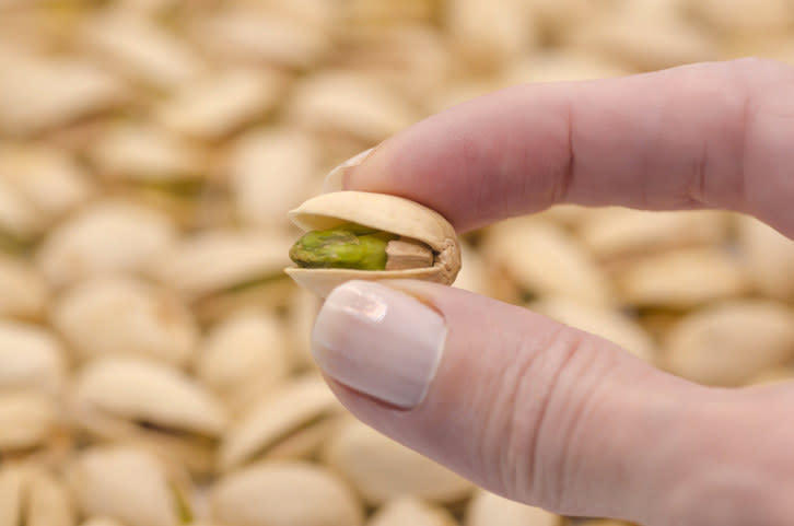 a pistachio in between fingers