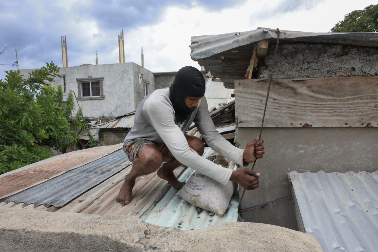 A man places sandbags along the roof as he prepares for the arrival of Hurricane Beryl in Kingston Jamaica.