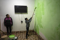 Elizabeth Mamani, 30, watches her son, Alexis, 10 paint the walls of their new house in Huancar, Jujuy Province, Argentina, Tuesday, April 25, 2023. The Andean town is prospering because of the work available in nearby lithium mines. (AP Photo/Rodrigo Abd)