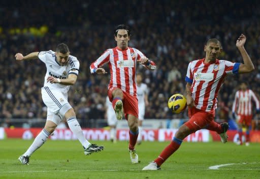 El francés del Real Madrid Karim Benzema (i) dispara marcado por el turco Arda Turan (C) y el argentino Cata Díaz, del Atlético de Madrid, en el derbi que el club blanco ganó 2-0 el 1 de diciembre de 2012 en su estadio Santiago Bernabeu. (AFP | pierre-philippe marcou)